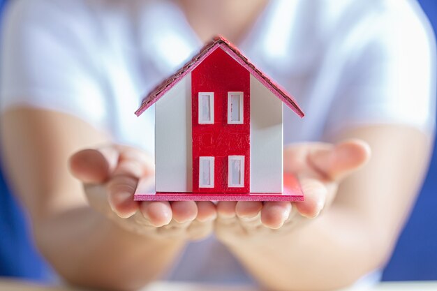 Menschliche Hände, die Modell des Traumhauses halten
