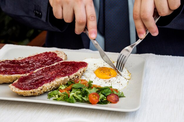 Menschliche Hand, die Ei während des Frühstücks schneidet