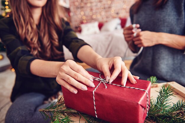 Menschliche Hand, die eine Schnur auf Weihnachtsgeschenk bindet