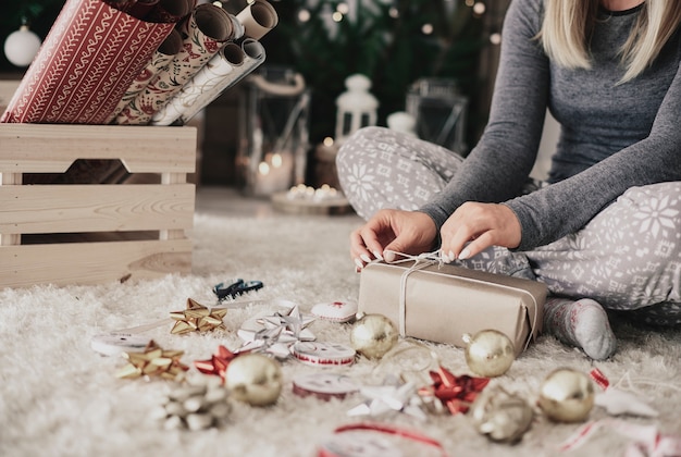 Menschliche Hand, die eine Schnur auf Weihnachtsgeschenk bindet