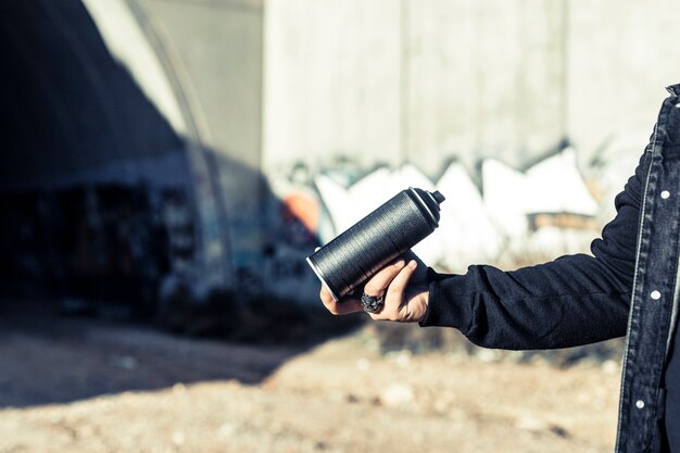 Menschliche Hand, die schwarze Aerosoldose hält