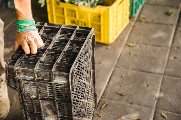 Menschliche Hand, die schwarze Plastikkiste am Marktplatz hält