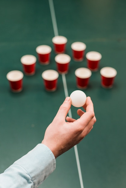 Kostenloses Foto menschliche hand, die weißen ball für das spielen des bier-pong-spiels hält