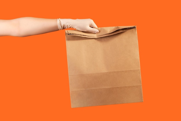 Menschliche hand in weißen handschuhen, die papierpakete mit essen halten und herstellen. sicheres konzept für die lebensmittellieferung.