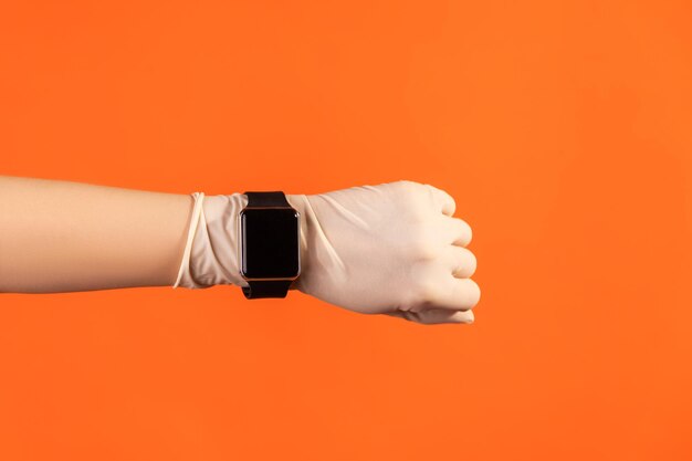 Menschliche hand in weißen op-handschuhen, die einen smartwatch-bildschirm halten und zeigen.