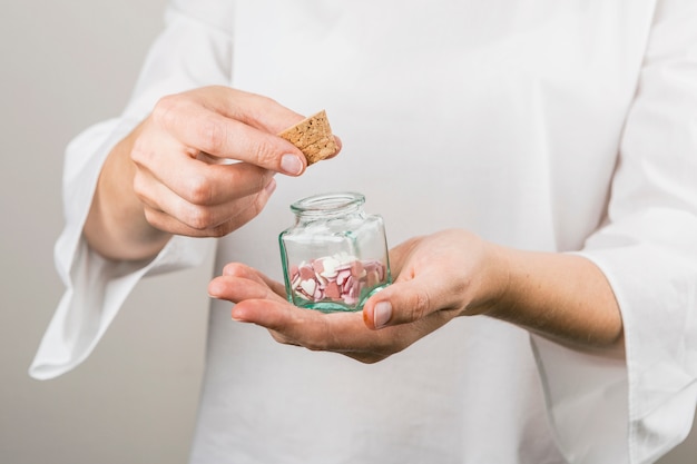 Menschlicher Holdingkorken und kleines Glas mit dekorativen Herzen