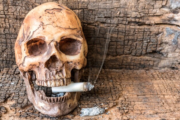 Menschlicher Schädel raucht Zigarette mit Rauch