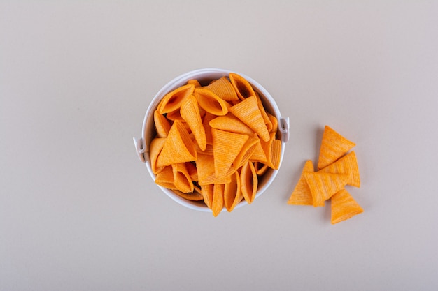 Metalleimer mit Dreieckschips auf weißem Hintergrund. Foto in hoher Qualität