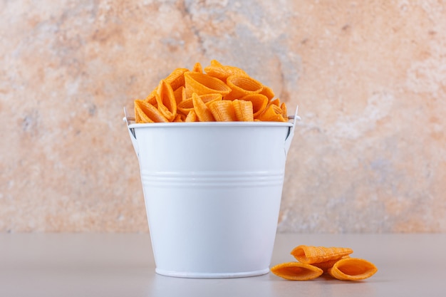 Metalleimer mit Dreieckschips auf weißem Hintergrund. Foto in hoher Qualität