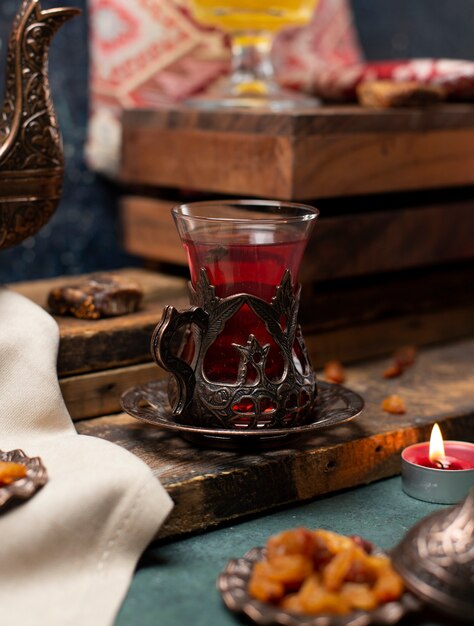 Metallisches dekoratives Glas schwarzer Tee auf dem hölzernen Brett