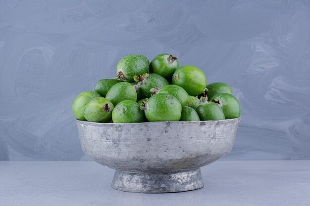 Metallvase gefüllt mit Feijoas auf Marmorhintergrund.