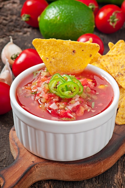 Kostenloses Foto mexikanische nacho-chips und salsa tauchen in eine schüssel auf holz