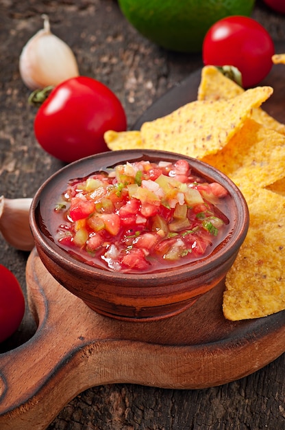 Mexikanische Nacho-Chips und Salsa tauchen in eine Schüssel auf Holz