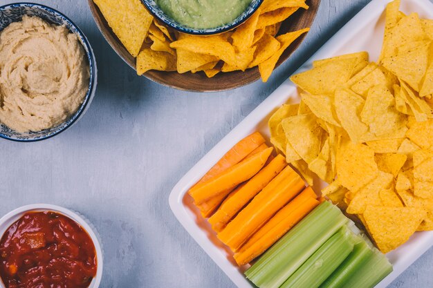 Mexikanische Nachos-Chips; Karotte mit Selleriestiel im Tablett mit Salsasauce in der Schüssel