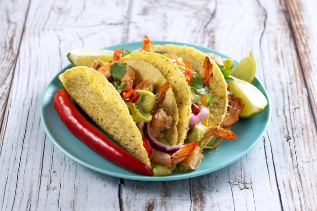 Mexikanische Tacos mit Garnelenguacamole und Gemüse auf Holztisch