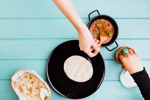 Mexikanisches Nahrungsmittelkonzept mit den Händen, die Burrito vorbereiten