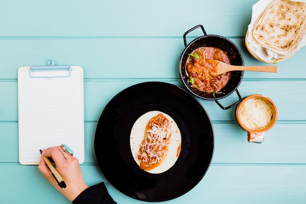 Mexikanisches Nahrungsmittelkonzept mit den Händen, die Burrito vorbereiten