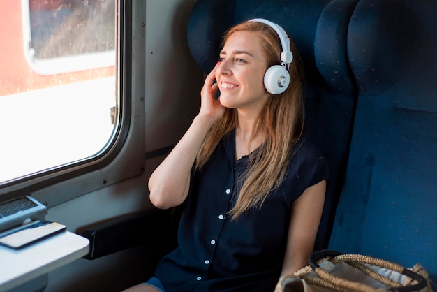 Mid Shot Frau sitzt im Zug und hört Musik