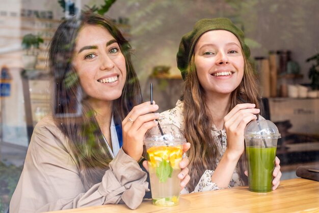 Mid Shot Frauen mit frischen Säften im Café