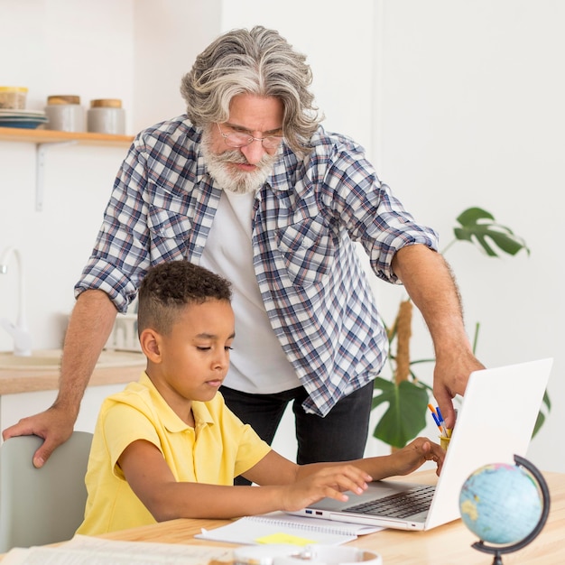 Mid Shot Lehrer sitzt neben Schüler am Laptop