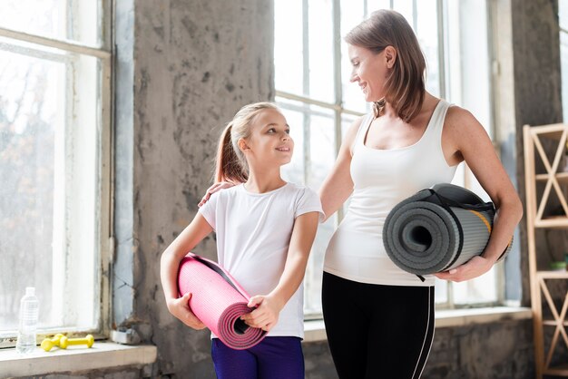 Mid Shot Mutter und Tochter halten Yogamatten