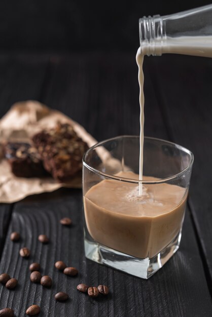 Milch aus der Flasche in ein Glas Kaffee gegossen