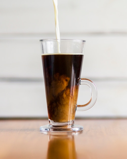 Milch gießt in heißen Kaffee