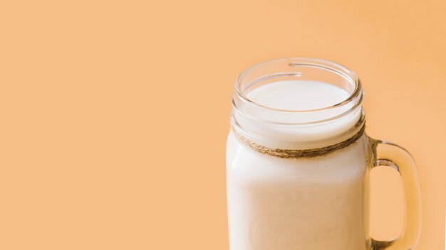 Kostenloses Foto milch im geöffneten glasgefäß über dem farbigen hintergrund