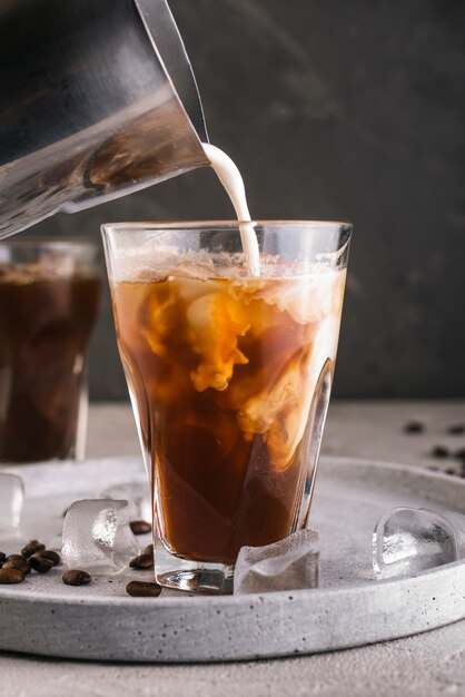 Milch mit Kaffee ins Glas gießen