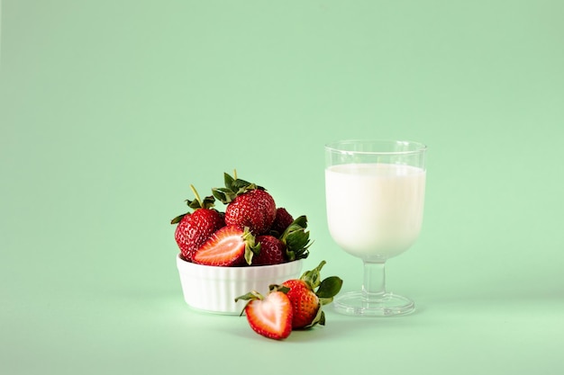 Milch und frische Erdbeeren auf grünem Hintergrund gesunde Ernährung und Ernährungslebensstil