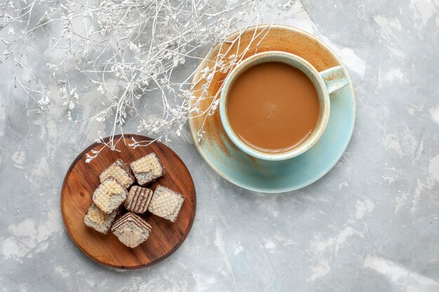 Milchkaffee der Draufsicht mit Schokoladenwaffeln auf dem süßen Zuckerkuchen-Keks des grauen Schreibtisches