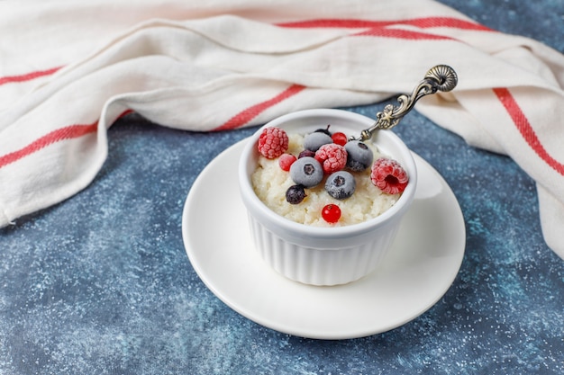 Kostenloses Foto milchreis mit gefrorenen blaubeeren und himbeeren in weißer schüssel