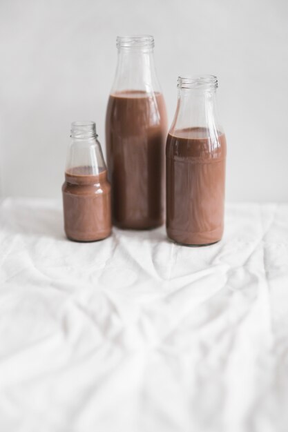 Milchschokoladenflaschen auf Tischdecke gegen weißen Hintergrund