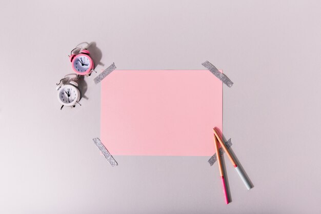 Mini-Wecker neben dem Satz rosa Briefpapier