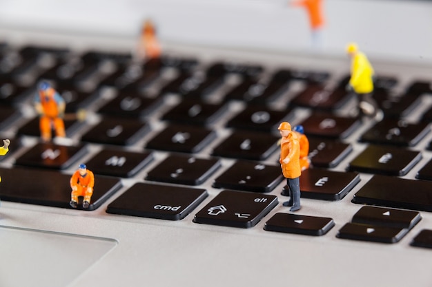 Miniatur-Arbeiter, die ein Laptop-Tastatur reparieren