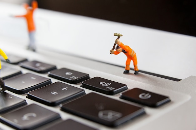 Kostenloses Foto miniatur-arbeiter, die ein laptop-tastatur reparieren