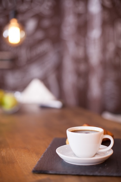 Minimalistische Komposition einer Tasse Kaffee auf einer schwarzen Steinplatte mit unscharfem Hintergrund. Leckerer Kaffee. Vintage-Kneipe.
