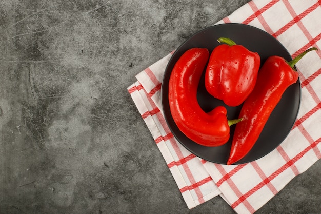 Minimalistisches Foto von roten Chilis auf einem schwarzen Teller. Draufsicht.
