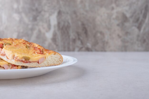 Minipizza auf Teller auf Marmortisch schneiden.