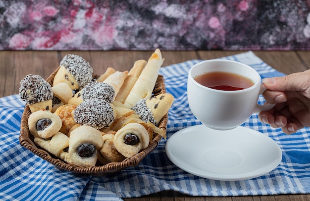 Mischung aus Keksen auf einer Platte, serviert mit einer Tasse Earl Grey Tee.