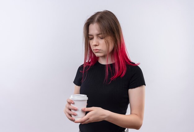 Mit geschlossenen Augen junges schönes Mädchen, das schwarzes T-Shirt hält, das Tasse Kaffee auf isolierter weißer Wand hält