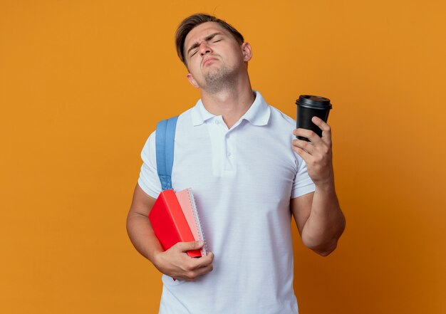 Mit geschlossenen Augen trauriger junger hübscher männlicher Student, der Rückentasche hält Buch hält