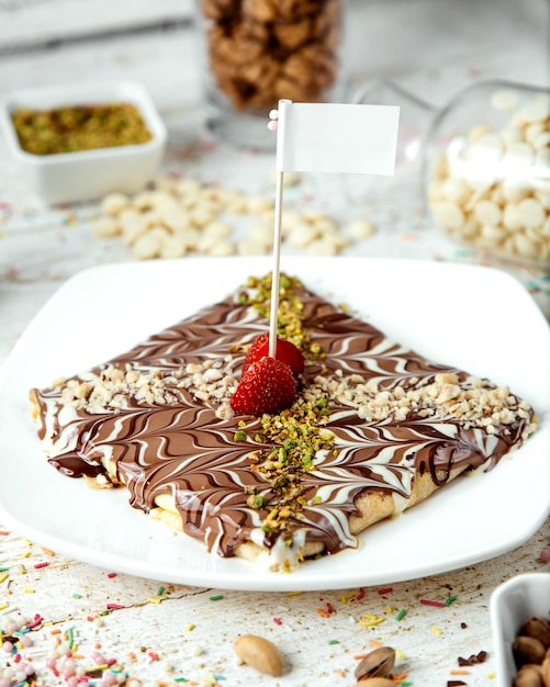 Mit Schokoladensirup überzogener Pfannkuchen mit geriebenen Pistazien bestreuen