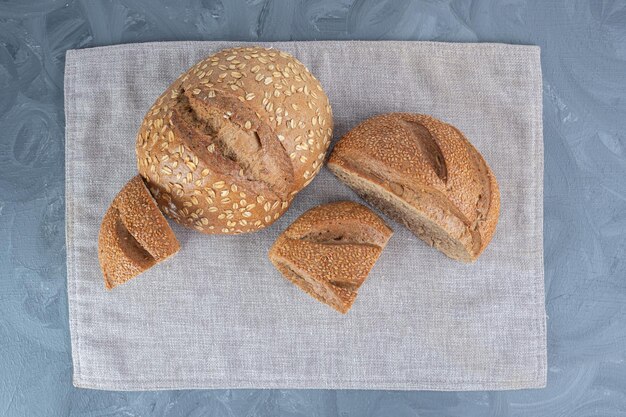 Mit Sesam bedeckte geschnittene Brotklumpen auf einem Handtuch auf Marmoroberfläche.