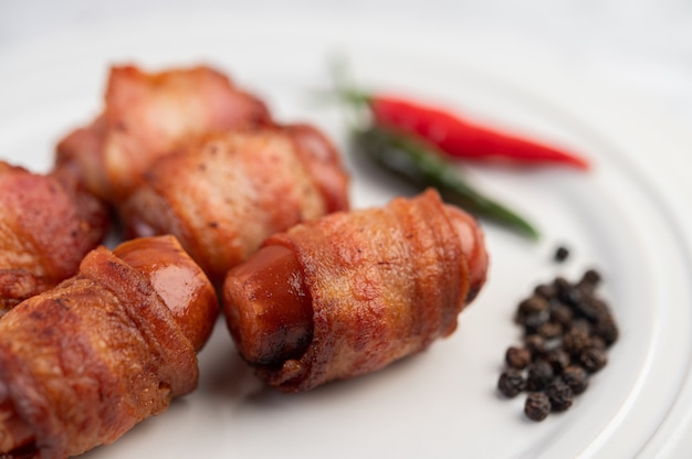 Kostenloses Foto mit wurst umwickelter schweinebauch auf einem weißen teller.