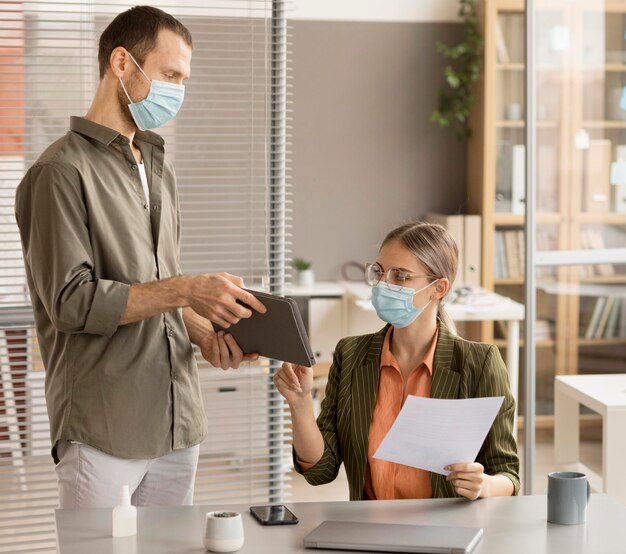 Mitarbeiter, die im Büro Gesichtsmasken tragen