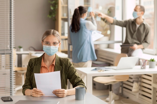 Mitarbeiter, die im Büro Gesichtsmasken tragen