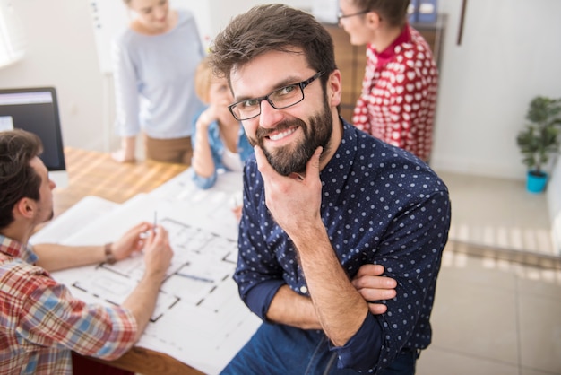 Mitarbeiter im Büro mit Architekturplänen und einem Computer. Manager-Konzept