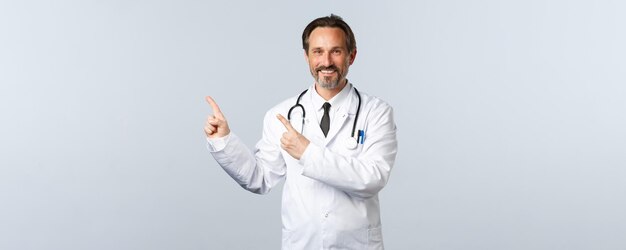 Mitarbeiter im Gesundheitswesen des Covid-Coronavirus-Ausbruchs und Pandemiekonzept lächelnd freundlich aussehender Arzt in...