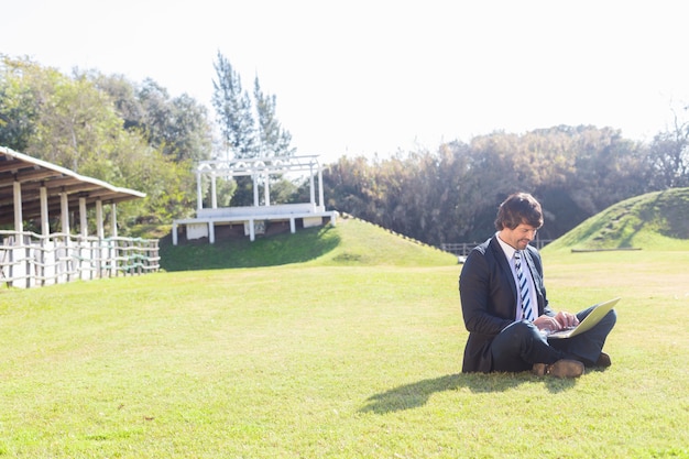 Mitarbeiter mit seinem Laptop arbeitet sitzen auf dem Rasen